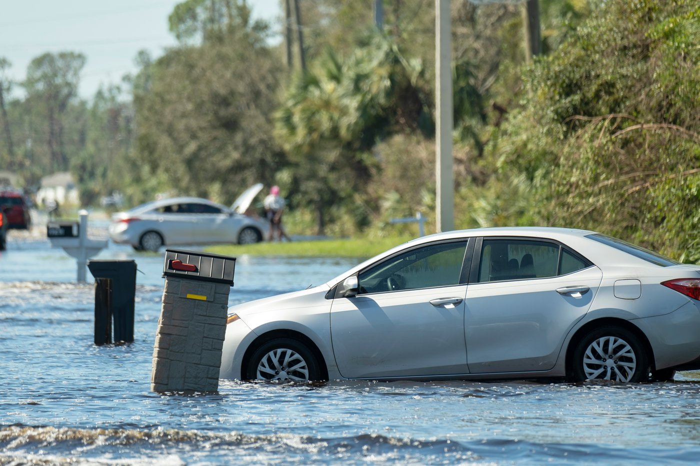 Silver sedan partially submerged in floodwater